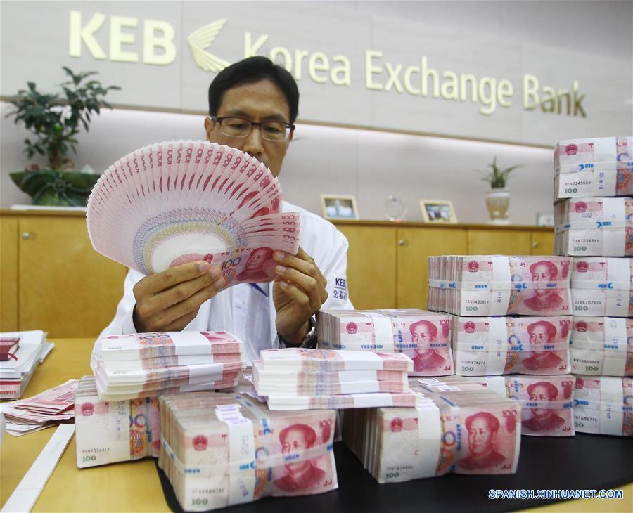 La foto tomada el pasado 27 de junio del a?o 2014 muestra a un empleado de un banco en la ciudad de Seúl mostrando unos billetes de Renminbi. El Fondo Monetario Internacional anunció el pasado 30 de noviembre de 2015 la inclusión el renminbi en la cesta de monedas de Derechos Especiales de Giro.