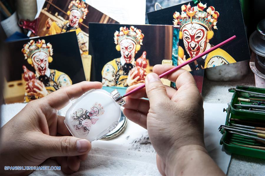 Imagen del 18 de julio de 2017 de Dong Xue, un artista de pintura interior, creando una botella de vidrio de tabaco pintada en el interior, en su vivienda en Shijiazhuang, capital de la provincia de Hebei, en el norte de China. La botella de tabaco de vidrio pintada en el interior es una artesanía tradicional china. El arte de pintura interior, que tiene una historia de más de 200 a?os, fue inscrita también como uno de los patrimonios culturales nacionales intangibles. Dong Xue y su hija han continuado estudiando la técnica y decidieron transmitirla. (Xinhua/Pu Dongfeng)