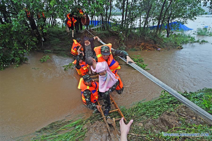 Bomberos rescatan a pobladores en la aldea Bajiapu, en el condado de Xiuyan de Anshan, en la provincia de Liaoning, en el noreste de China, el 4 de agosto de 2017. Una lluvia torrencial afectó al condado el jueves y viernes, da?ando caminos, instalaciones de electricidad y cultivos en algunos municipios. Un total de 18,900 personas han sido trasladadas a lugares seguros, y la ciudad ha iniciado el nivel 1 de respuesta de emergencias para enfrentar las posibles inundaciones. (Xinhua/Yang Qing)