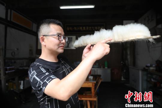 Jiang Guangming， un cocinero de este tipo de tofu, mide la longitud de los filamentos para determinar si el tofu ha fermentado completamente.[Foto: Fan Chengzhu/ Chinanews.com]