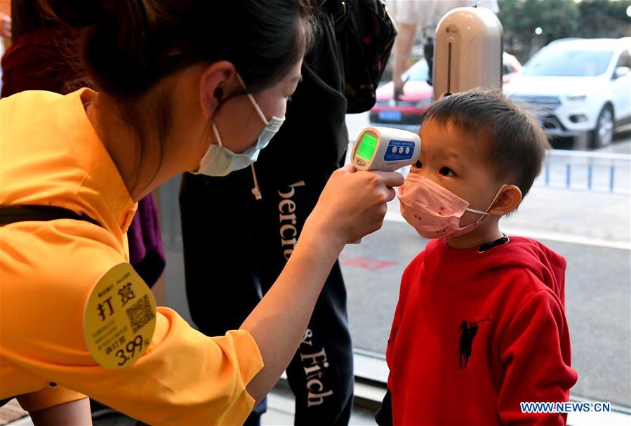 Un miembro del personal comprueba la temperatura corporal de un ni?o en un restaurante en Zhengzhou, provincia de Henan. 