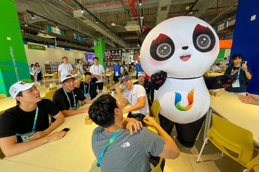 Un empleado del comedor disfrazado de la mascota Rongbao, festeja el cumplea?os de los jugadores de República de Corea en la Villa de la 31a edición de verano de los Juegos Mundiales Universitarios de la FISU, en Chengdu, en la provincia de Sichuan, en el suroeste de China, el 30 de julio de 2023. (Xinhua/Shen Bohan)