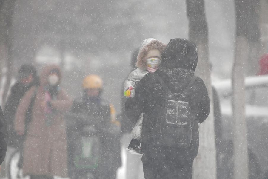 Un peatón carga a un ni?o en un día nevado en Qiqihar, en la provincia nororiental china de Heilongjiang, el 25 de noviembre de 2024. (Xinhua/Wang Yonggang)