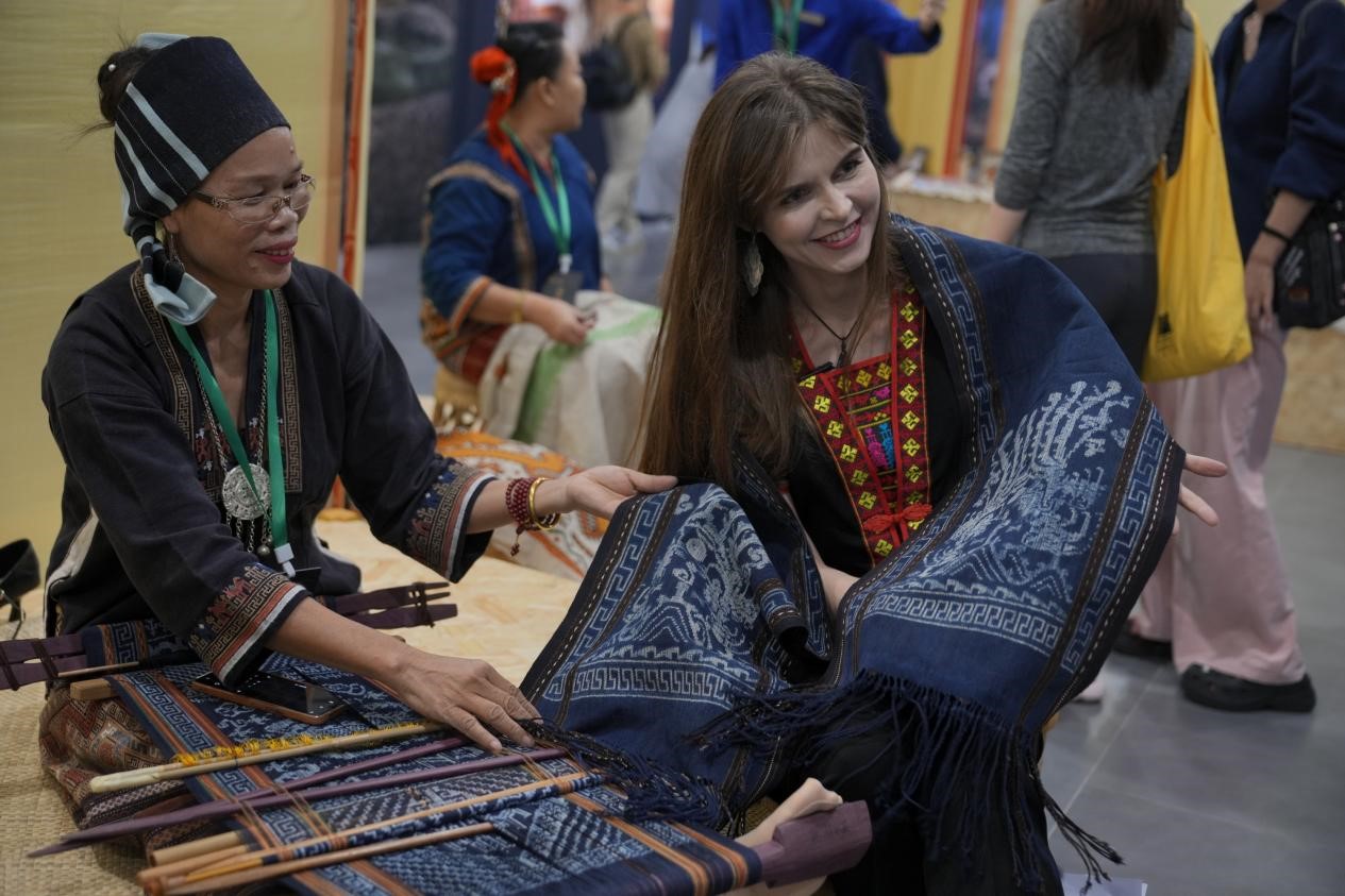 Una mujer rusa se maravilla con las técnicas textiles tradicionales de Li en la Semana Cultural Mundial del Brocado y el Bordado de Hainan 2024 (4.a) celebrada en la provincia de Hainan, en el sur de China, el 8 de noviembre de 2024. (Foto de Zhang Mao/Diario del Pueblo digital)