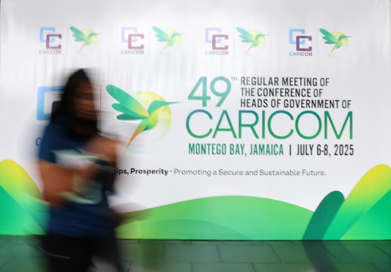 Imagen del 6 de julio de 2025 de una mujer pasando junto a una valla publicitaria of la 49a Reunión Ordinaria de la Conferencia de Jefes de Gobierno de la Comunidad del Caribe (CARICOM) en Montego Bay, Jamaica (Xinhua/Li Mengxin)